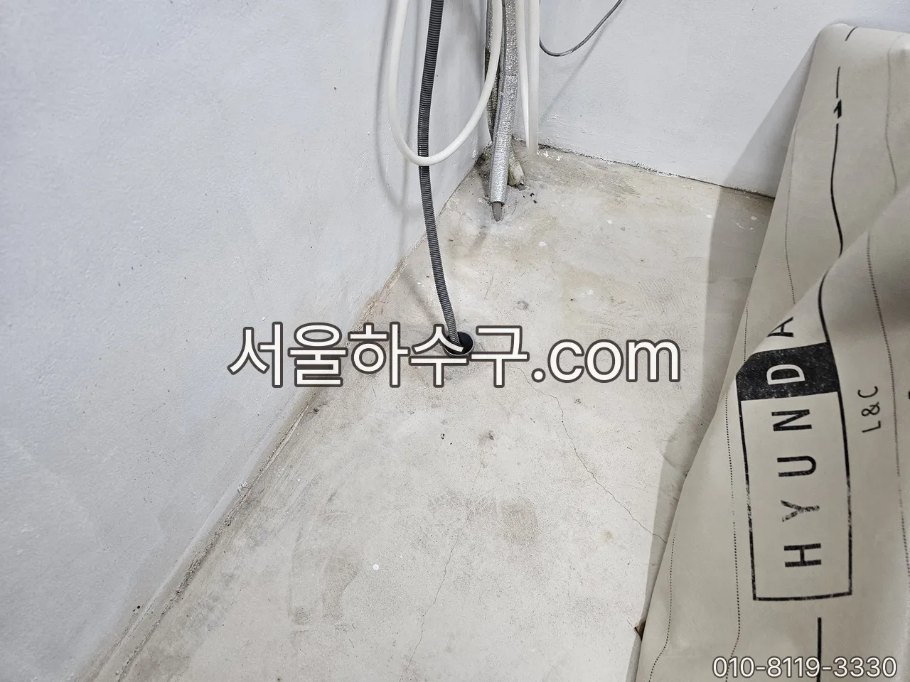 세탁기 배수호스 끝이 바닥 배관에 꽂힌 자리 — 남은 물이 얼어 막히는 지점