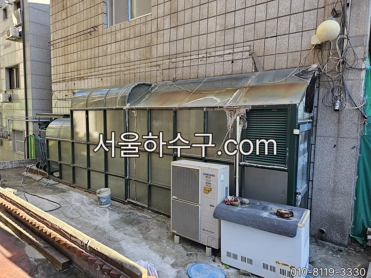 실외기 옆 드레인 호스 끝단 — 끝이 물에 잠기면 배수가 멈추는 자리